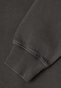Tejido de sudadera gris oscuro con puños acanalados, que muestra una textura suave y un acabado sin costuras. El tejido parece suave y duradero.