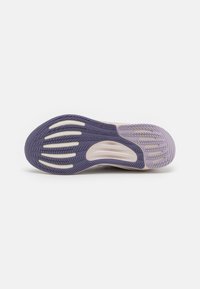 Suela de zapato de goma morada con un patrón de agarre texturizado, que presenta líneas curvas y recortes. Acentos en tonos claros cerca del centro.