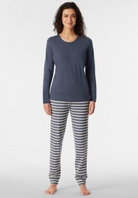 Maglietta a maniche lunghe blu navy abbinata a pantaloni del pigiama bianco e grigio a righe. Materiale in cotone, design attillato e morbida consistenza.