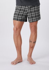 Juodi ir balti languoti bokseriai, pagaminti iš lengvos medžiagos. Yra elastinė juosmens juosta ir laisvas kirpimas, su languotu raštu.