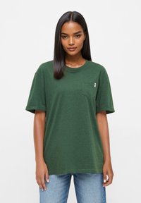 Groene katoenen t-shirt met een ronde halslijn, korte mouwen en een borstzak. Zachte textuur, comfortabele pasvorm en minimale merkdetails.