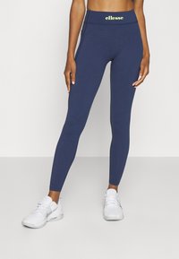 Mörkblå leggings med hög midja och en logo i ljusgul. Tillverkade av stretchigt material, designade för komfort och flexibilitet.