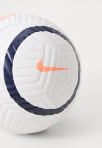Nike fodbold med en hvid overflade med et tekstureret mønster, fremhævet af et marineblåt design og en fremtrædende orange Nike swoosh.