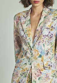 Blazer floreale caratterizzato da molteplici colori tra cui viola, blu e giallo. Realizzato in tessuto leggero, con revers a punta e tasche frontali.