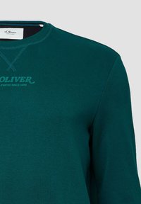 Felpa verde in cotone con colletto a girocollo, maniche lunghe e una stampa del logo discreta sulla parte anteriore, accompagnata da dettagli di cucitura coordinati.