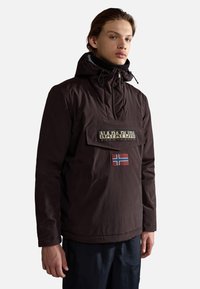 Brown waterproof pullover with a hood, featuring a front pocket, logo patch, and Norway flag accent. Smooth texture, modern fit.