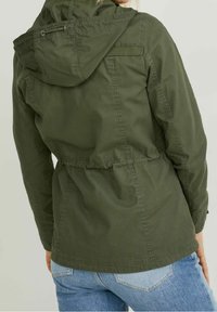 Olivově zelená lehká bunda s kapucí, elastickým pasem a viditelným šitím; má neformální, pohodlný střih.