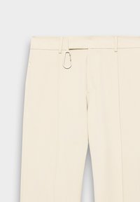 Beige bukser med en glat tekstur, udstyret med en bæltestrop og en sølvfarvet karabinlås detalje. Én sidelomme med lynlås.
