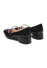Chaussures en cuir noir à petit talon avec un bout pointu et des détails de sangle courbés. Fini brillant avec des talons blocs en caoutchouc et une doublure lisse.