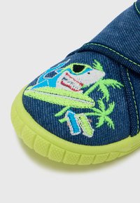 Pantof slip-on din denim cu un design de rechin albastru și verde. Talpă verde lime, material texturat și broderie proeminentă cu palmieri și plăci de surf.