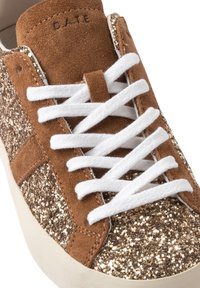 Sneaker in suede marrone con lacci bianchi e pannelli in tessuto glitter dorato, che mostrano la parte superiore frontale e la scritta "DATE" in rilievo sulla linguetta.