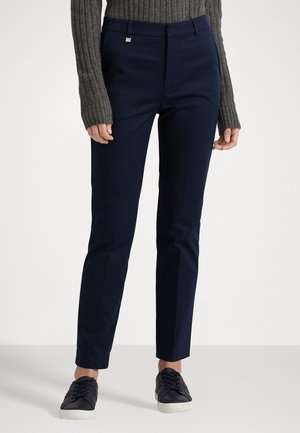 Navy blue tailored trousers with a smooth fabric, flat front, and pockets. Paired with a gray ribbed sweater and dark sneakers.
