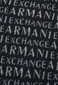 Tessuto nero con un motivo ripetitivo delle parole "ARMANI" e "EXCHANGE" in un colore grigio a contrasto, realizzato con un lavoro a maglia testurizzato.