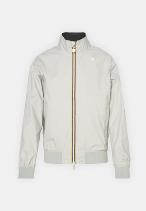 Helehalli hall sinine bomber-jakk kõrge krae, tõmblukk ja soonikkoes mansetid. Tõmbluku juures on kollase ja tumesinise aktsentidega detailid. Sile tekstuur.