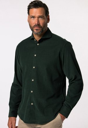 Camisa de pana verde oscura con collar abotonado, mangas largas y botones claros en el frente, con un sutil patrón texturizado.