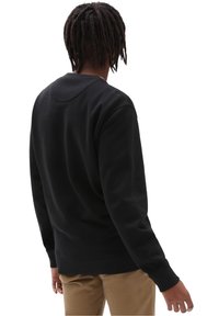Felpa nera con maniche lunghe, colletto girocollo e polsini a costine. Tessuto morbido e vestibilità rilassata, vista da dietro.