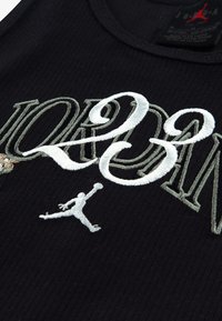 Μαύρο ριμπ αμάνικο τοπ με κεντημένο κείμενο «JORDAN» και λογότυπο Jumpman σε λευκό και γκρι, με στρογγυλή λαιμόκοψη και υφασμάτινη υφή.