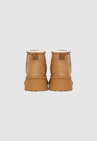 Beige Wildleder-Stiefeletten mit strukturiertem Finish, weicher Innenausstattung, verstärktem Rückenzug und einer dicken Gummisohle mit Profilmuster.
