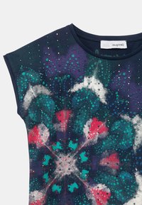 Navyblaues ärmelloses Oberteil mit buntem abstraktem Blumenmuster in Teal, Rot, Weiß und Lila, verziert mit kleinen reflektierenden Nieten.