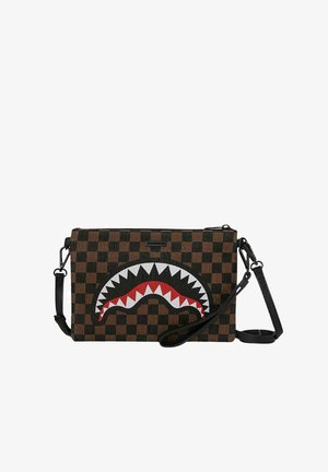 Bolso marrón a cuadros con un diseño prominente de boca de tiburón en blanco y negro, con detalles en rojo. Incluye una correa negra desmontable.