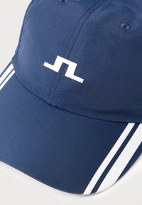 Gorra de marino con un diseño estructurado, que presenta un logo blanco y dos rayas blancas a lo largo del visor. Fabricada con una tela suave de acabado mate.