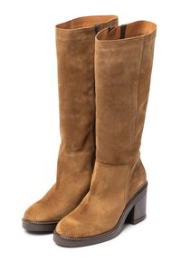Botas de ante marrón hasta la rodilla con tacón apilado, que cuentan con una cremallera lateral y costuras limpias a lo largo de la suela. Textura suave con un acabado liso.