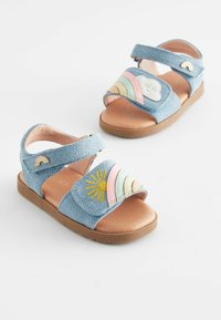 Ljusblå denimsandaler med kardborreband, med färgglad regnbågs- och solsbroderi på framsidan och en brun sula.