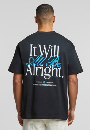 Sort bomulds-T-shirt med store hvide og blå bogstaver på ryggen, der står "Det hele skal nok gå." Korte ærmer og afslappet pasform.