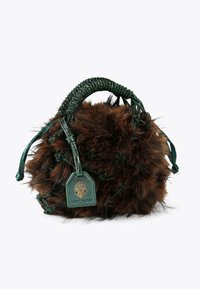 Borsa a mano di pelliccia marrone con forma rotonda, manico in perline verdi decorate e un’etichetta in pelle con logo. Aspetto testurizzato e morbido.