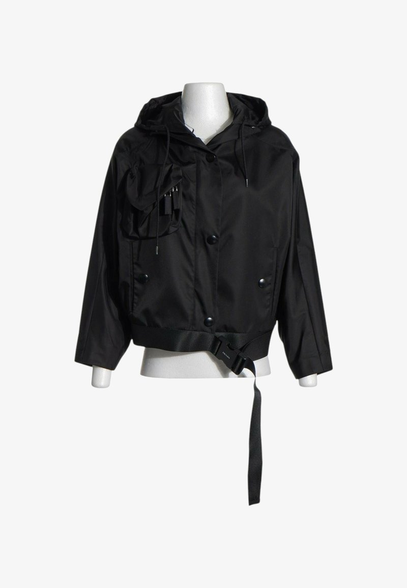 Veste noire à capuche avec boutons sur le devant, une poche poitrine zippée et une ceinture ajustable à l'ourlet, présentée sur un mannequin.