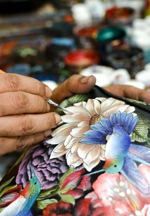 Handgeschilderd op een donkere achtergrond met kleurrijke bloemen, gedetailleerde kolibries en ingewikkelde ontwerpen. Gereedschap en verfpotten op de achtergrond.
