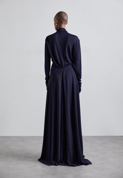 Long navy dress with a high neckline, long sleeves, and a draped back. Made of soft fabric, it features a smooth, flowing silhouette.