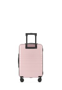 Hard-shell carry-on suitcase in pastel pink with vertical grooves, black accents, a retractable handle, and four wheels for mobility.