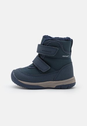 Botte d'hiver enfant imperméable bleu marine avec deux bandes Velcro, semelle texturée et doublure douce en polaire visible au niveau de la cheville.