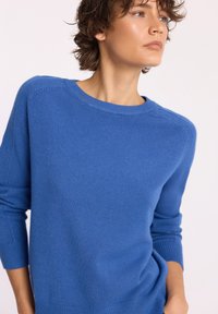 Niebieski sweter dziany z okrągłym dekoltem, długimi rękawami, ściągaczami i fakturowym wykończeniem. Miękki materiał i luźny krój.