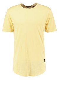 Camiseta de algodón amarilla con cuello redondo y mangas cortas, con un dobladillo recto y una pequeña etiqueta de marca en el lado inferior.