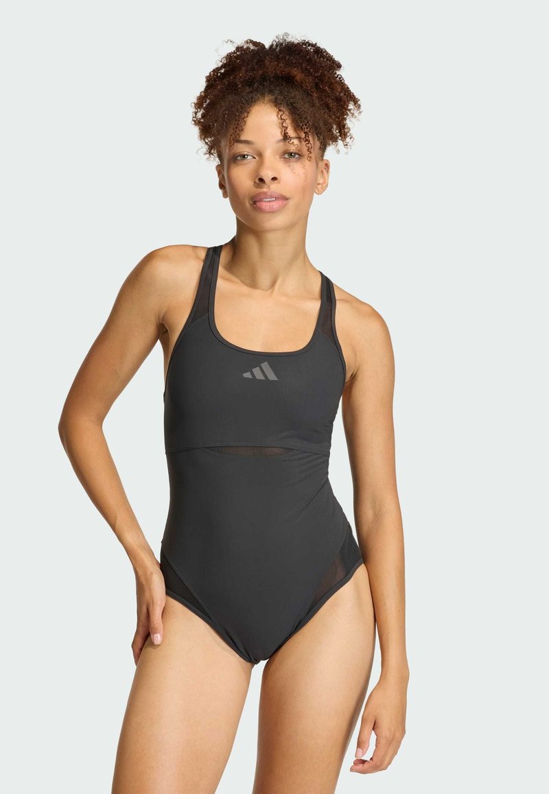 Čierne plavky s priliehavým dizajnom, sieťkovými akcentmi a širokými ramienkami so diskrétnym logom na hrudi. Hladký materiál a vysoké vykrojenie nohavíc.