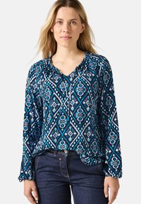 Langärmlige Bluse in Marineblau mit einem geometrischen Muster in Blau und Helllila; verfügt über einen gerafften Kragen und ein lässiges Design.