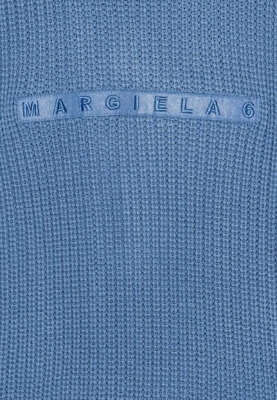 Modrá pletená látka s horizontálne prišitým filcovým štítkom, zobrazujúcim text "MARGIELA 6" v zodpovedajúcej modrej niťi.