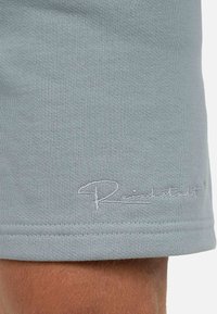Lichtgrijze katoenen shorts met een geribbelde textuur en een gestikt logo in het wit aan de zoom, met een eenvoudig ontwerp en een relaxte pasvorm.