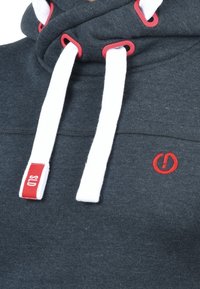 Sudadera con capucha de color gris oscuro y cuello alto, con cordones blancos y detalles en rojo. Presenta un pequeño logo rojo y una etiqueta con SLD.
