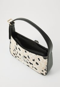 Small handbag featuring a beige textured surface with black spots, a black leather strap, and a zippered interior with multiple compartments.