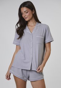 Grauene Baumwoll-Pyjama-Set mit kurzen Ärmeln und einer Tasche. Mit weißem Piping entlang des Kragens, der Knöpfe und dem Saum der Shorts.