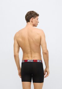 Czarne bokserki z szerokim, markowym pasem w kolorze czerwonym i białym. Odzież ma gładką fakturę i dopasowany krój.