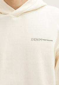 Crème hoodie met een zachte textuur, met het "DENIM TOM TAILOR" logo in het grijs op de borst. Casual stijl met een ontspannen pasvorm.