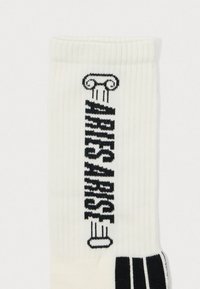 White ribbed socks featuring black graphic text and column design. The design includes a striped pattern near the ankle.