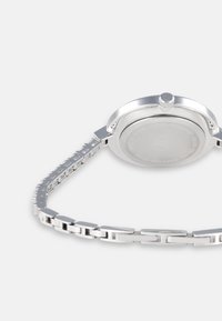 Silberner Metalluhren mit rundem Gehäuse, glatter Oberfläche und einem verlinkten Armband. Verfügt über eine auffällige Krone und eine polierte Oberfläche.