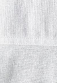 Light gray fabric with a knitted texture, featuring a subtle horizontal seam and a soft, slightly heathered appearance.