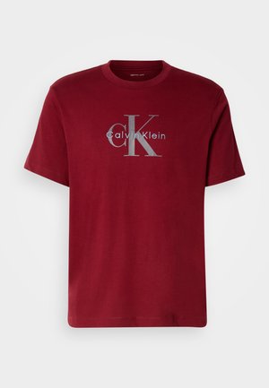 Bordo bombažna majica s srebrnim logotipom "Calvin Klein" in velikim stiliziranim "CK" na sprednji strani; okrogla izreza in kratki rokavi.