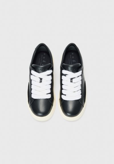 Black leather sneakers with white laces, round toe, and cream-colored sole. Features minimal branding on the tongue and side panels.